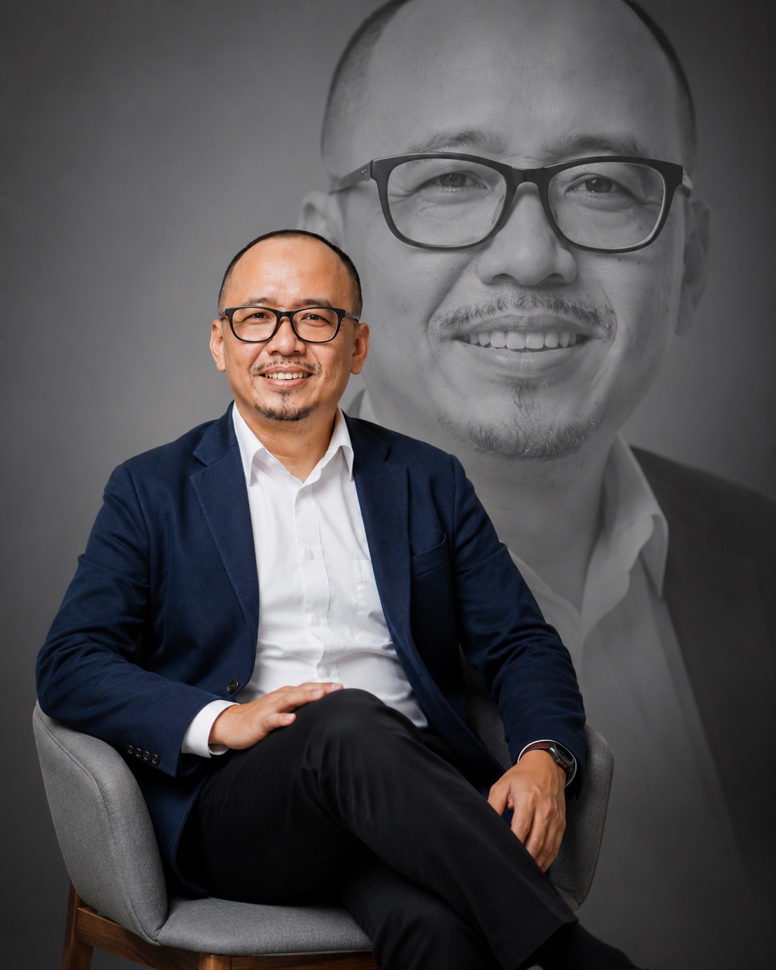 Dr. Muhammad Sobirin, M.M.Pd (Kang Sob) duduk tersenyum mengenakan blazer biru tua
